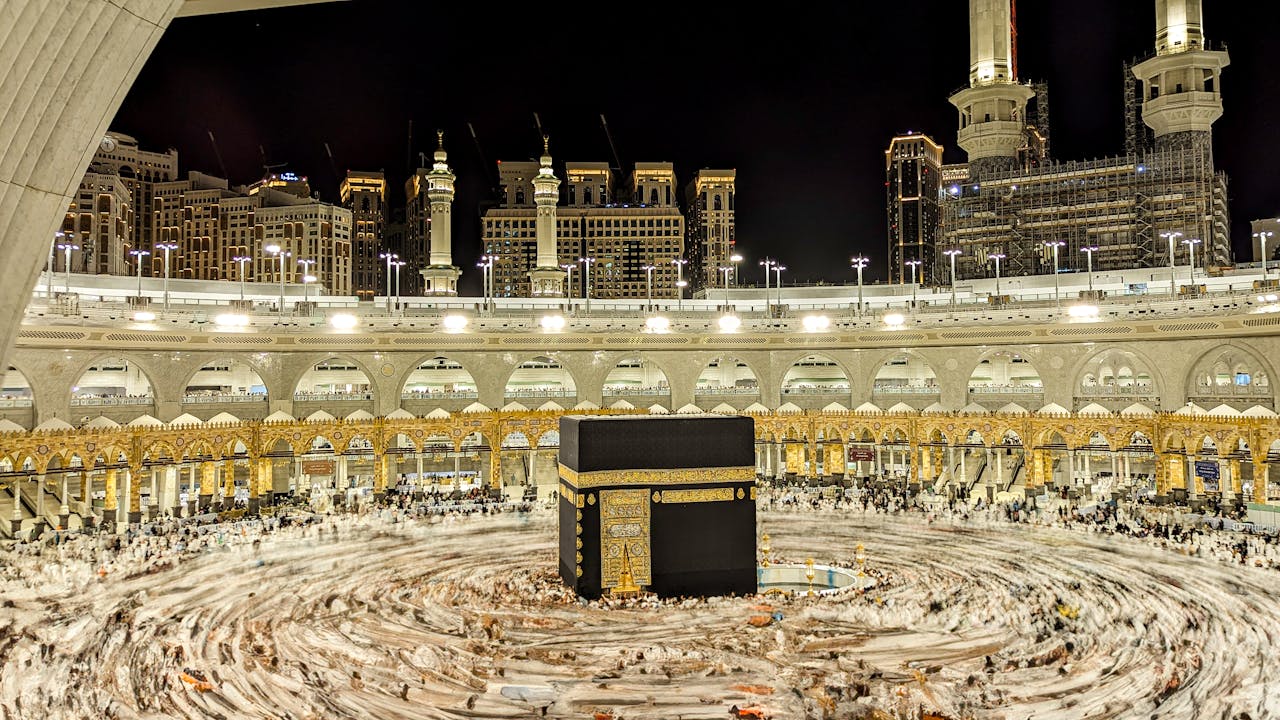 Vibrant night view of the Kaaba in Mecca, capturing Islamic architecture and worshippers.